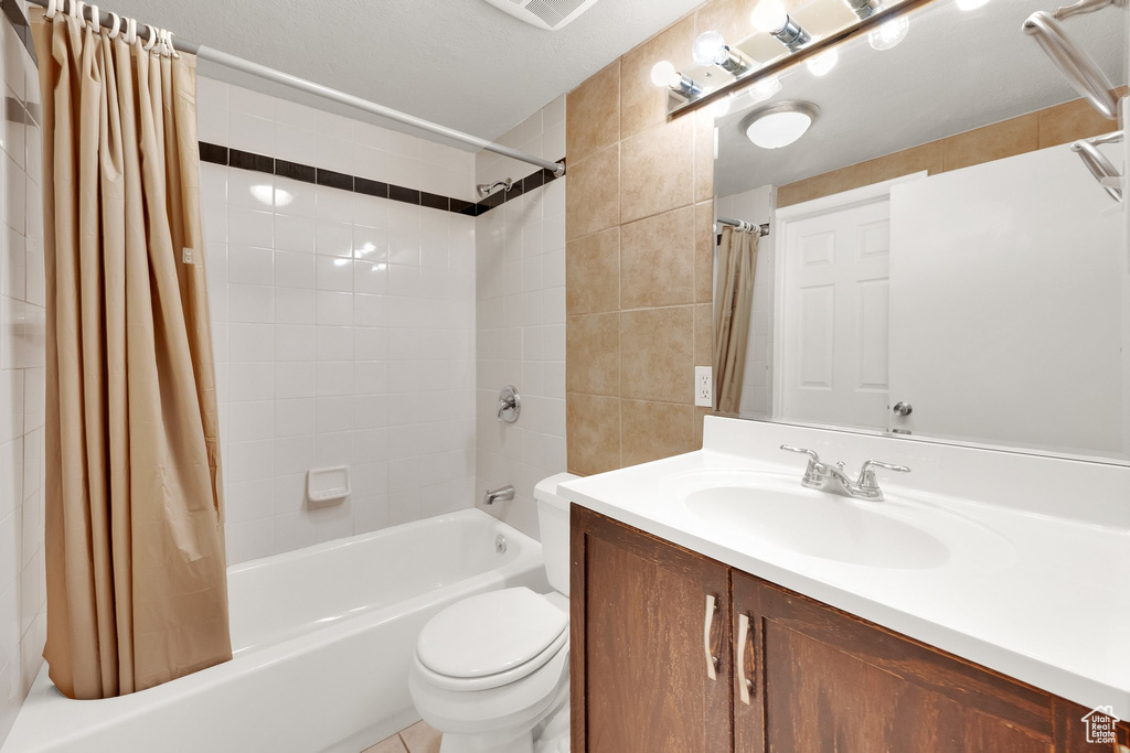 Full bathroom with shower / bath combination with curtain, vanity, and toilet