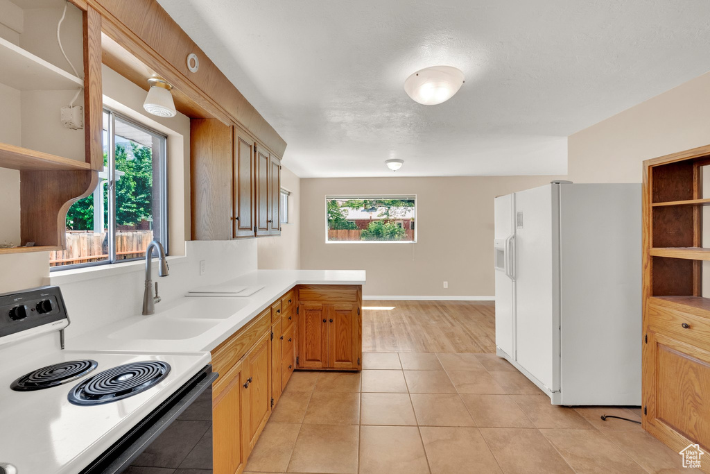 Kitchen featuring white refrigerator with ice dispenser, open shelves, range with electric stovetop, and plenty of natural light