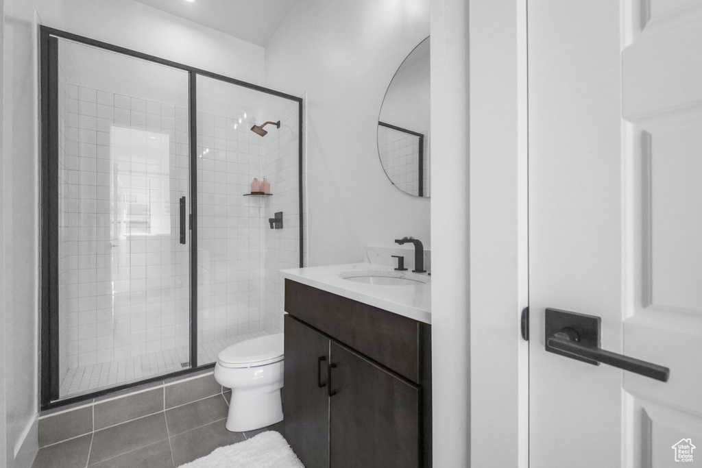 Bathroom featuring vanity, a shower stall, toilet, and tile patterned flooring