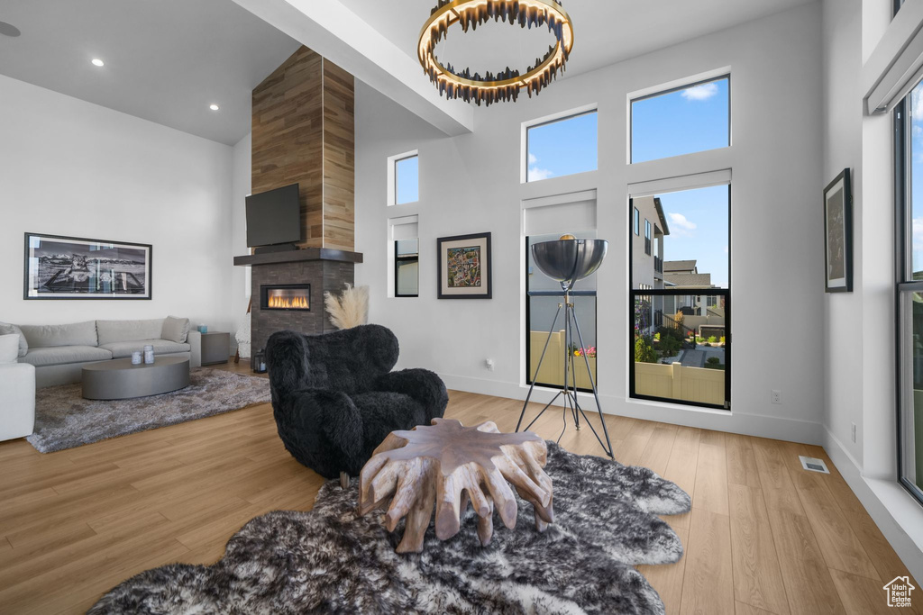 Living room with a towering ceiling, a fireplace, wood finished floors, baseboards, and recessed lighting