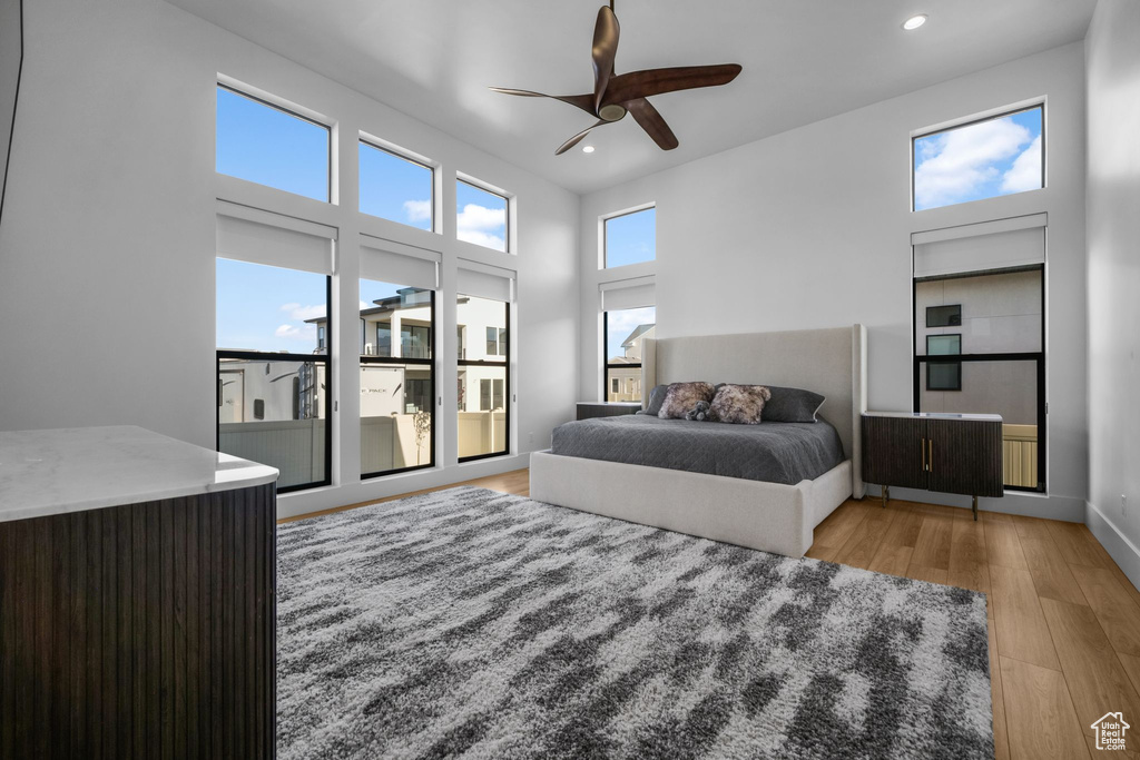Bedroom featuring recessed lighting, light wood-style floors, a ceiling fan, a high ceiling, and baseboards