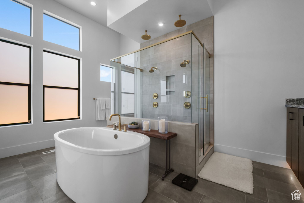 Full bath with a stall shower, tile patterned floors, a freestanding bath, baseboards, and vanity