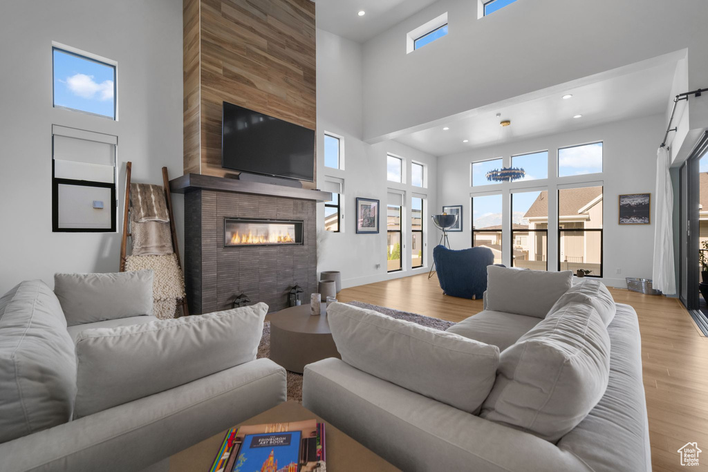 Living room with a towering ceiling, a large fireplace, wood finished floors, recessed lighting, and baseboards