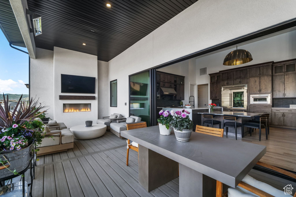 Wooden deck featuring outdoor dining space, an outdoor living space with a fireplace, and a sink