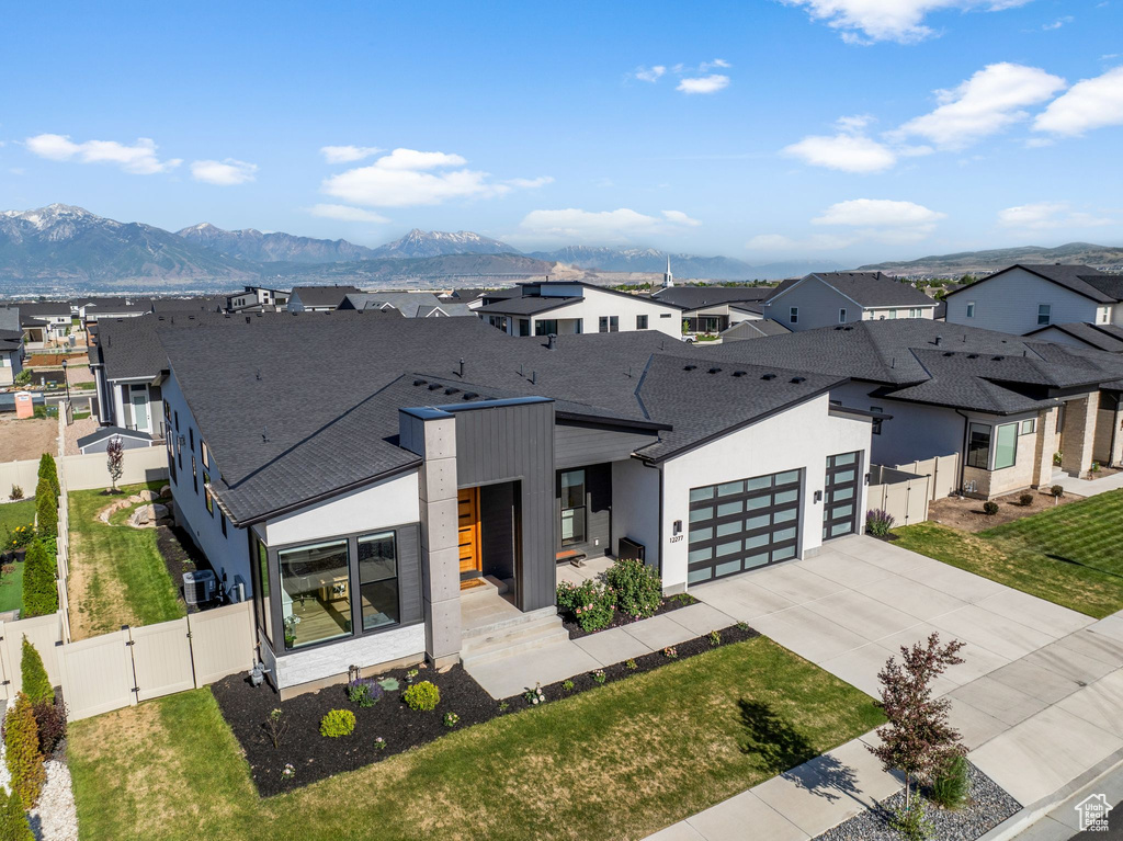 Contemporary home with a gate, a residential view, concrete driveway, and a shingled roof