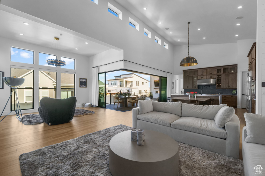 Living area featuring a towering ceiling, wood finished floors, and recessed lighting