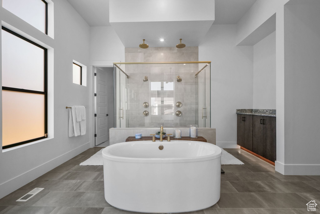 Bathroom with a shower stall, a freestanding tub, baseboards, and vanity