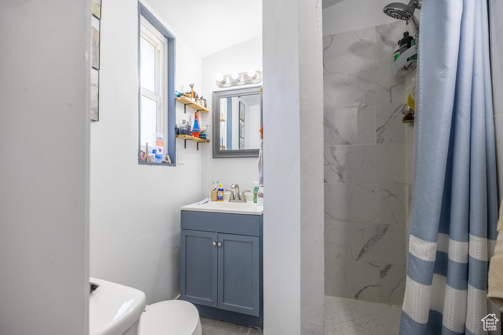 Bathroom with a marble finish shower, vanity, toilet, and lofted ceiling
