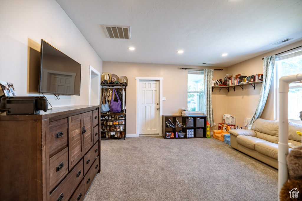 Living area with light carpet and recessed lighting