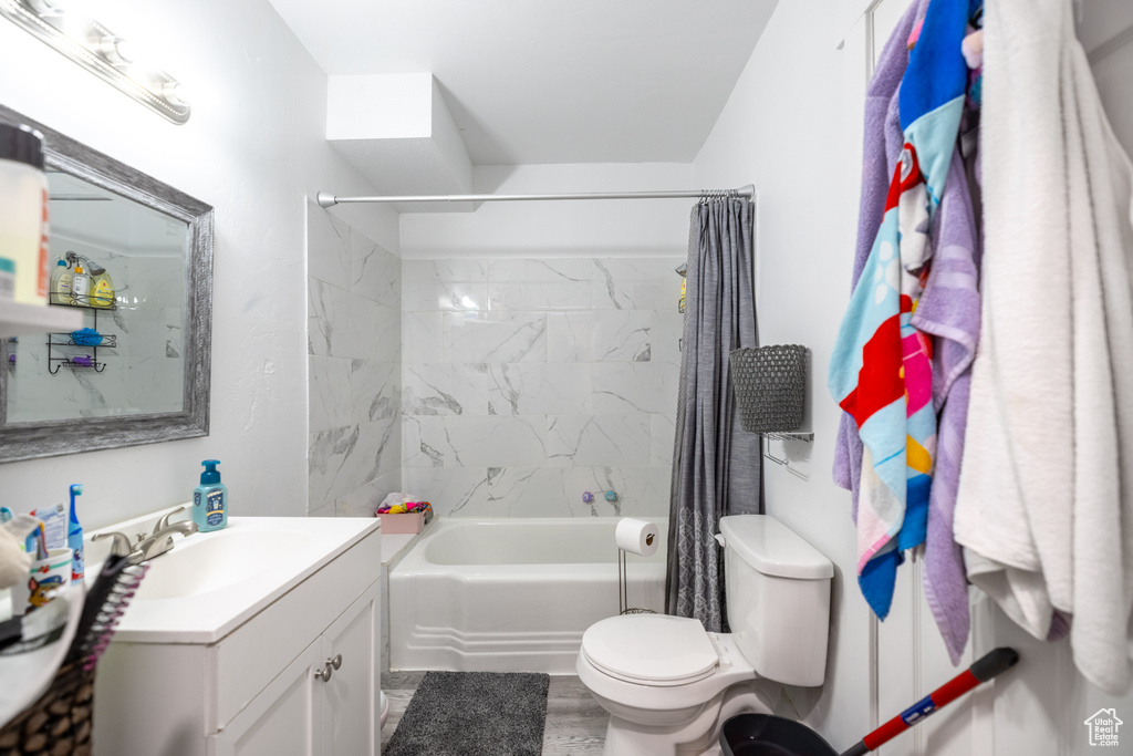 Bathroom with vanity, shower / bath combination with curtain, and toilet