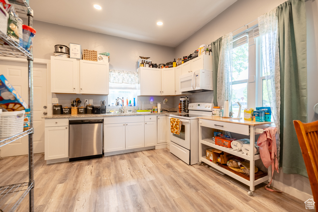 Kitchen featuring white appliances, plenty of natural light, light wood-type flooring, recessed lighting, and a sink