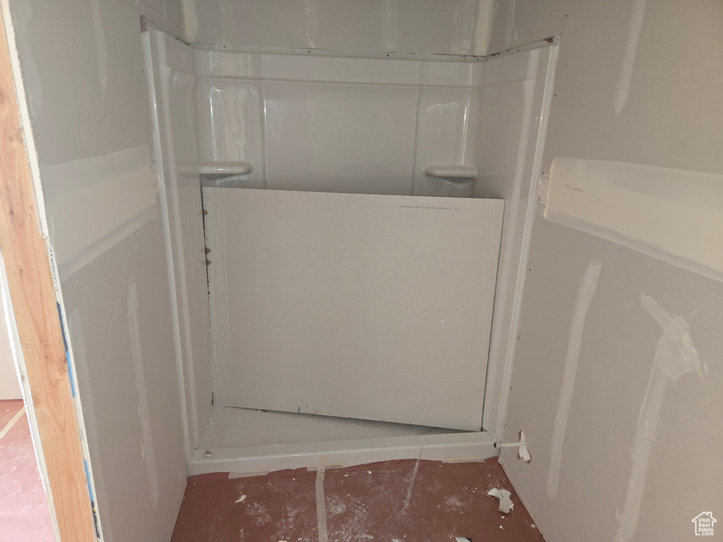Bathroom with a shower stall and unfinished concrete floors