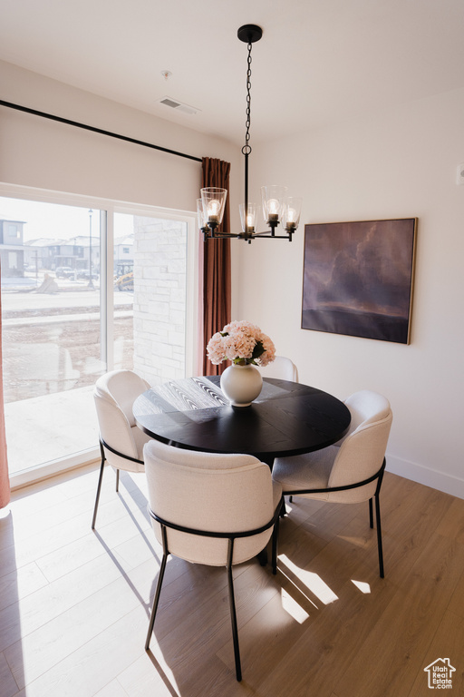 Dining area with a chandelier, light wood finished floors, and baseboards