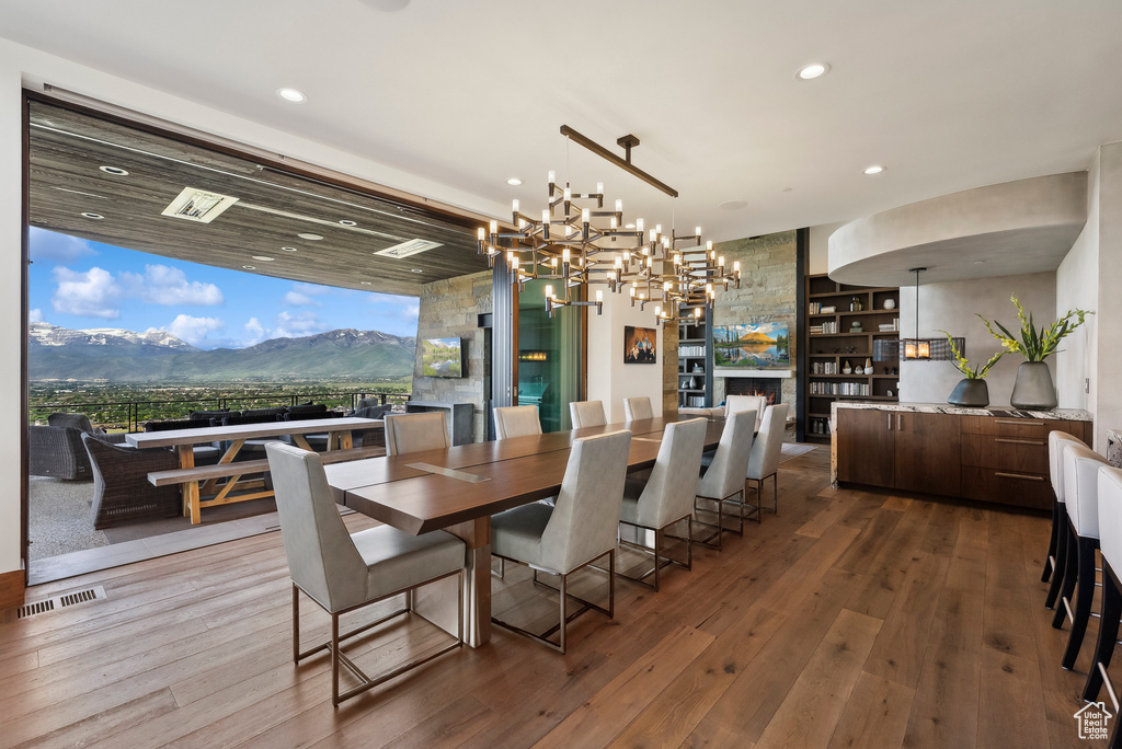 Dining area featuring hardwood / wood-style floors, recessed lighting, a chandelier, a lit fireplace, and a mountain view