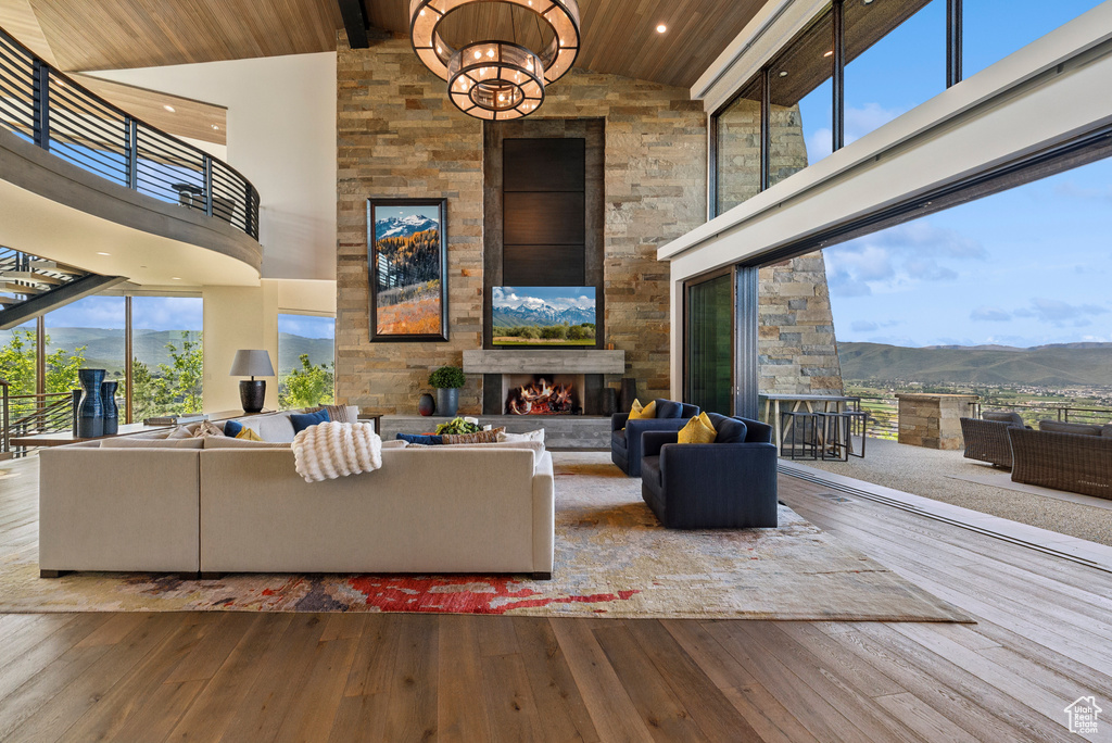 Living area featuring a mountain view, an outdoor stone fireplace, wood ceiling with exposed beams, high vaulted ceiling, and hardwood / wood-style floors