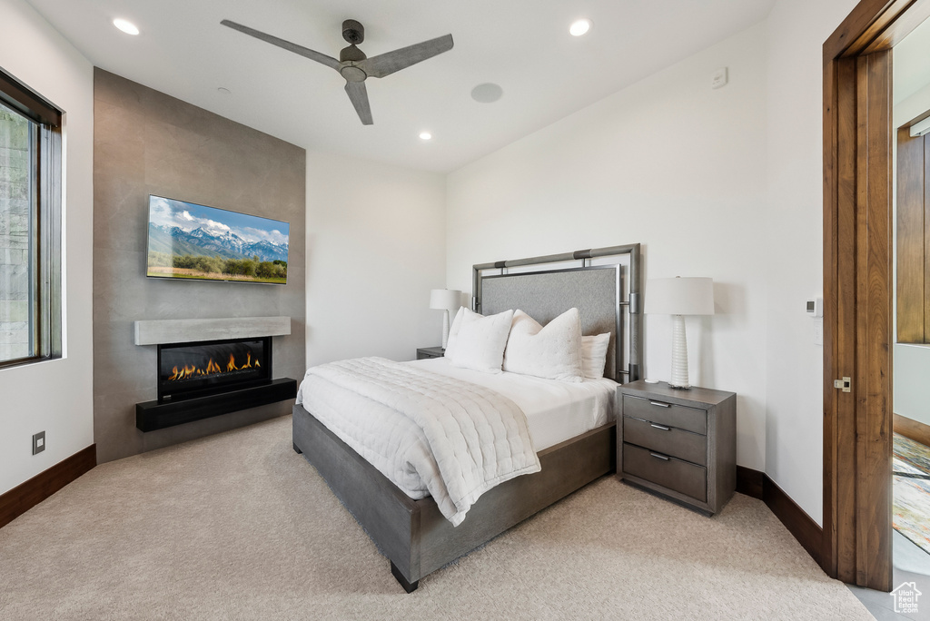 Bedroom with light carpet, a glass covered fireplace, recessed lighting, baseboards, and ceiling fan