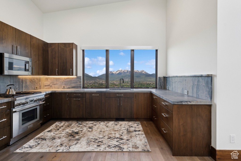 Kitchen with stainless steel appliances, a high ceiling, a mountain view, a sink, and decorative backsplash