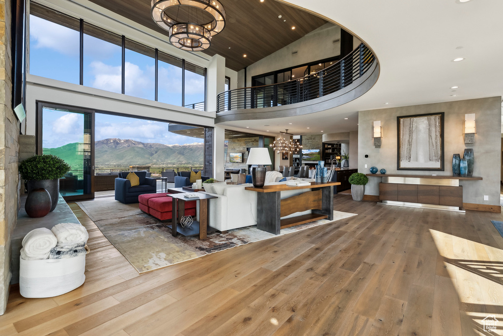 Living room with a chandelier, hardwood / wood-style floors, a mountain view, a high ceiling, and recessed lighting
