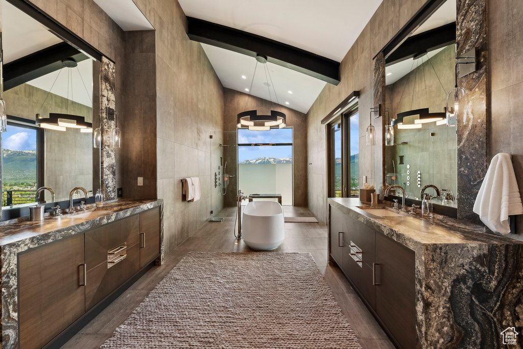 Full bathroom with two vanities, a freestanding tub, beam ceiling, tile walls, and recessed lighting