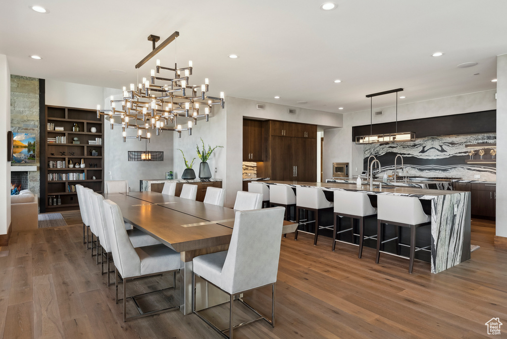 Dining space with wood finished floors, recessed lighting, a chandelier, and built in shelves