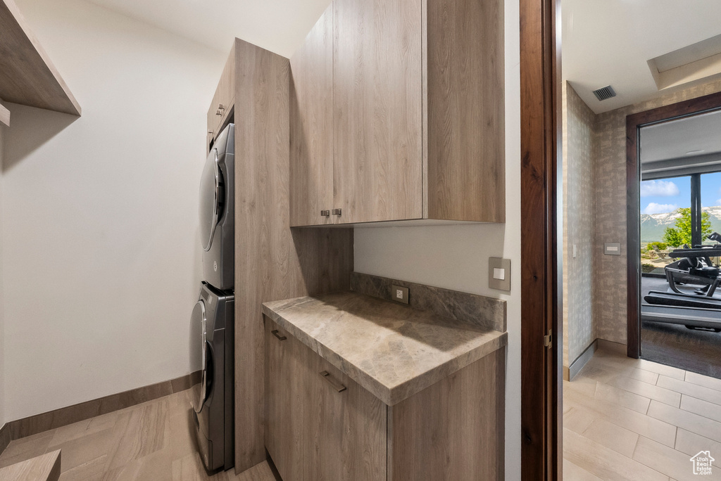 Kitchen featuring estacked washer and dryer, modern cabinets, baseboards, light countertops, and light brown cabinets