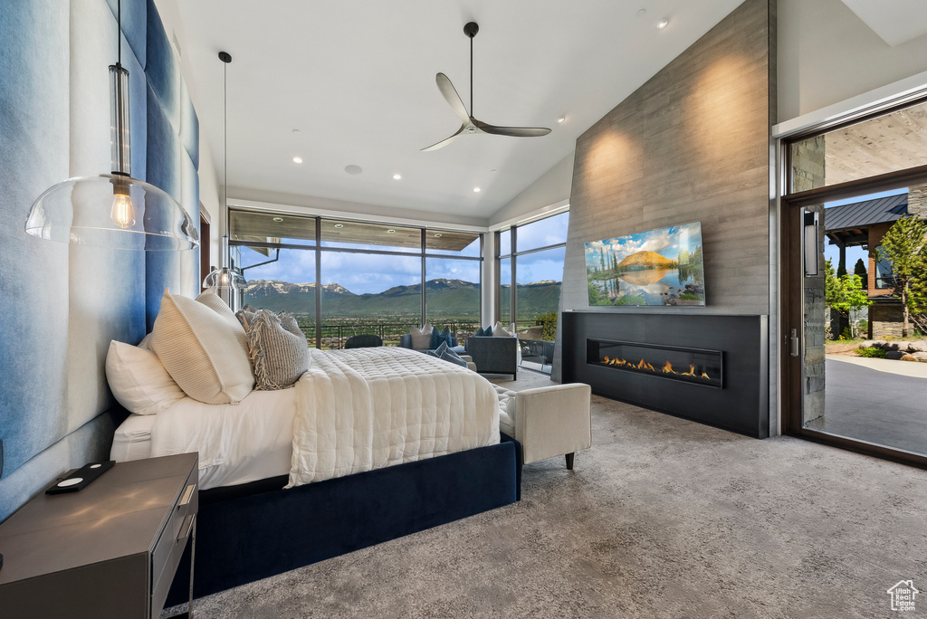 Carpeted bedroom with access to exterior, vaulted ceiling, a glass covered fireplace, and recessed lighting