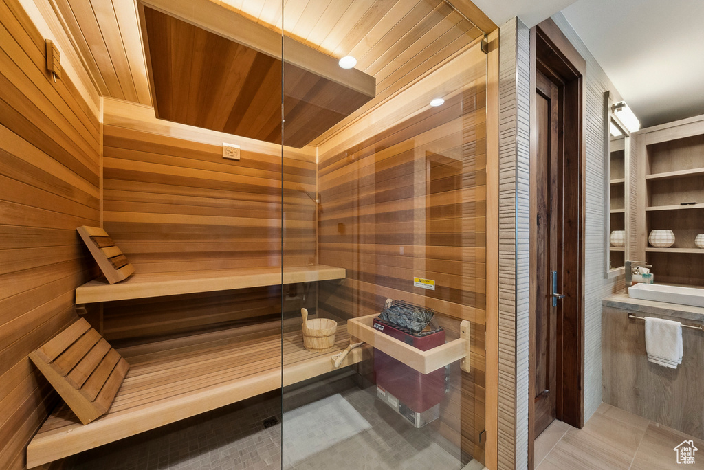 Sauna with wooden walls, wooden ceiling, and tile patterned floors