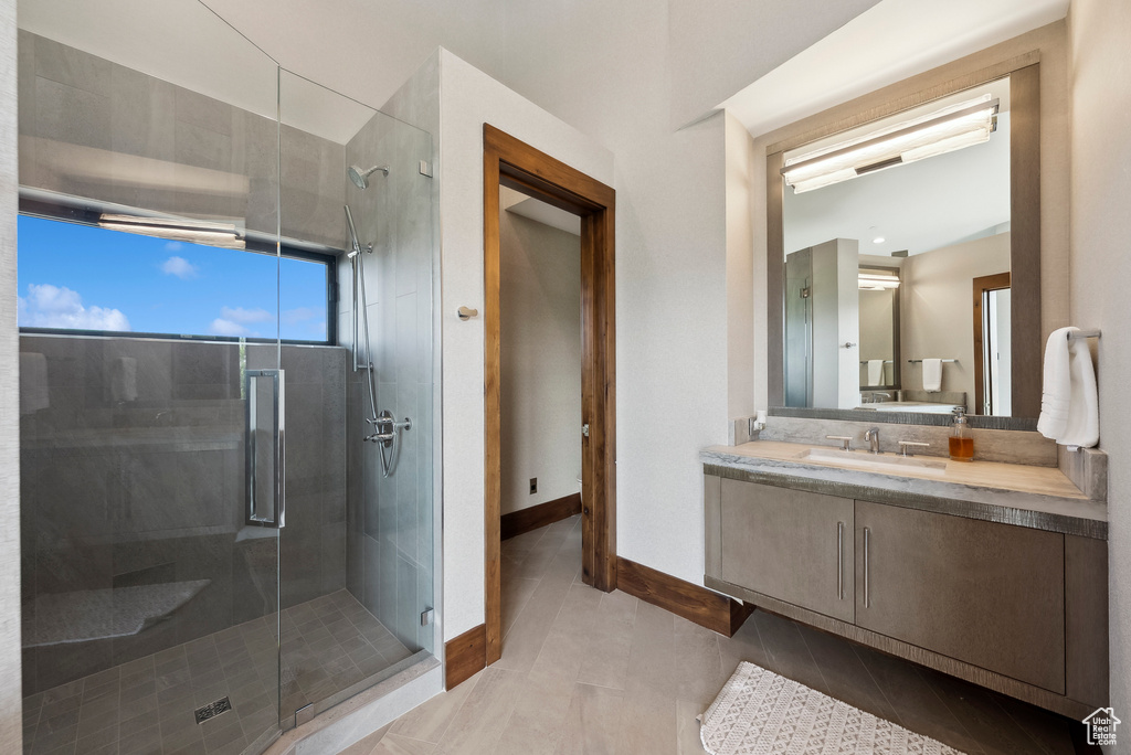 Bathroom with a stall shower, vanity, baseboards, and tile patterned flooring