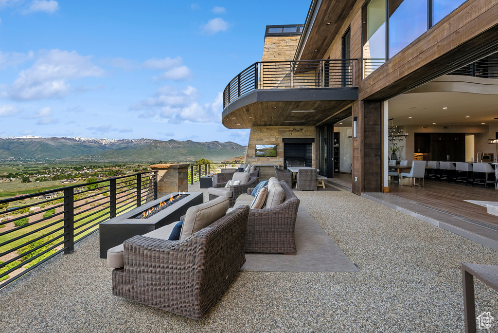 View of patio with a balcony, an outdoor living space with a fire pit, and a mountain view