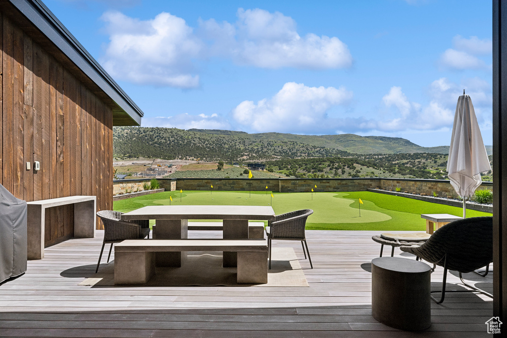 Deck featuring an area to practice putting, a mountain view, and golf course view