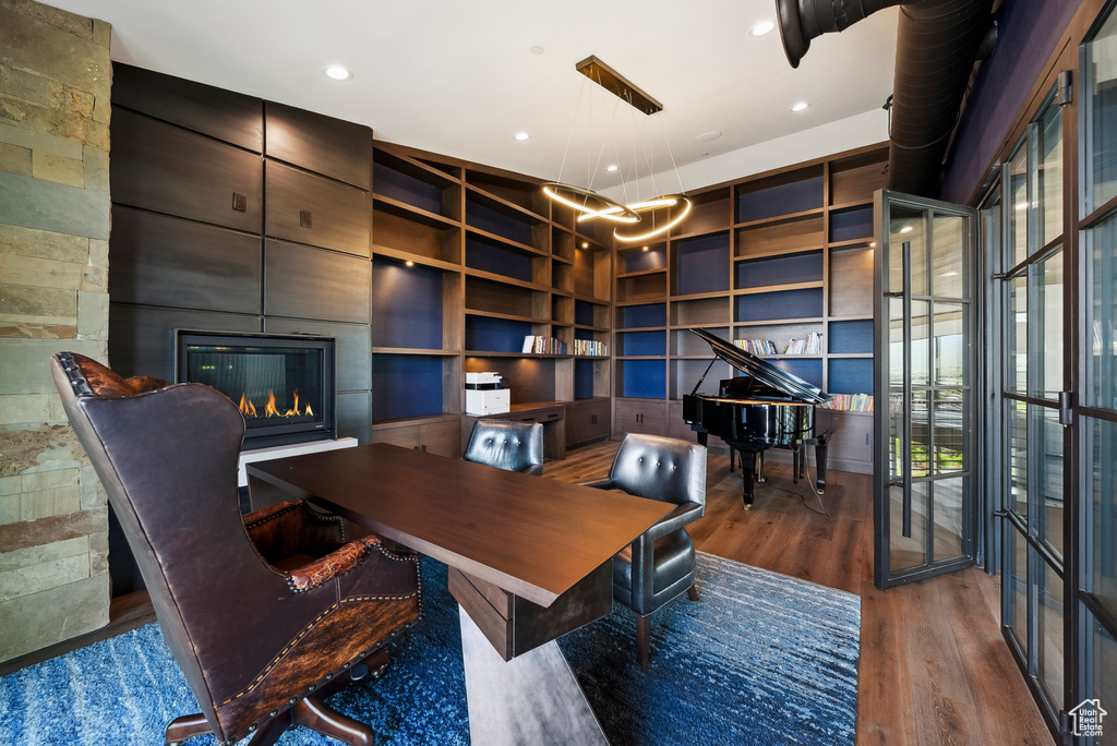 Home office featuring a fireplace, wood finished floors, built in shelves, and recessed lighting