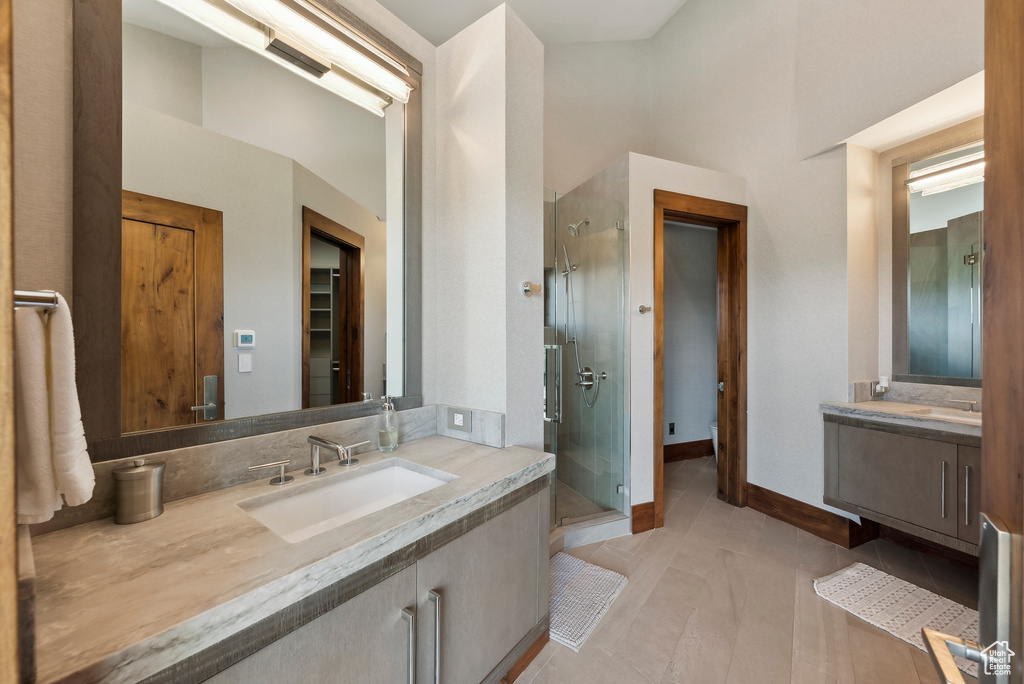 Full bath featuring a stall shower, vanity, tile patterned flooring, and baseboards