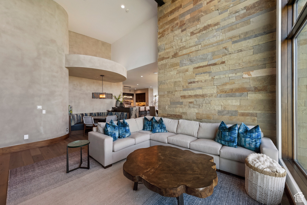 Living room with high vaulted ceiling, wood finished floors, and baseboards