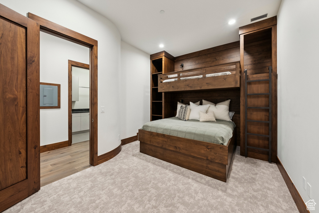 Bedroom featuring baseboards, recessed lighting, light carpet, light wood finished floors, and electric panel