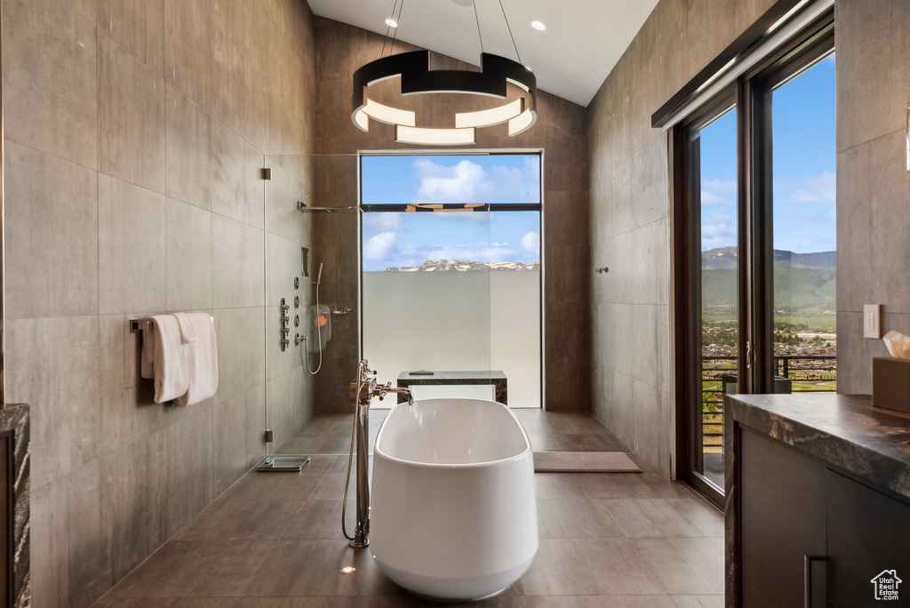 Bathroom featuring tile walls, a soaking tub, walk in shower, vanity, and tile patterned floors