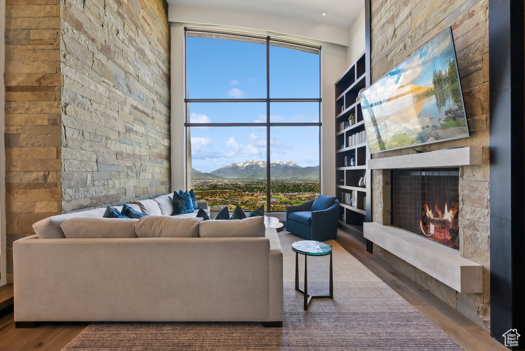 Living area with wood finished floors, a fireplace, and a towering ceiling