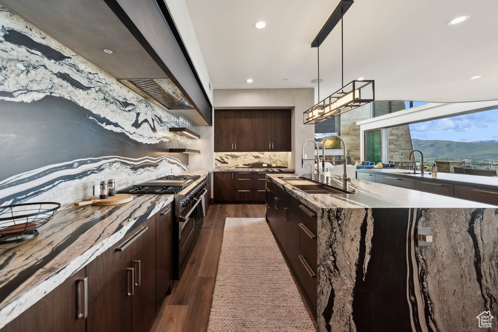 Kitchen featuring premium range hood, dark wood-type flooring, a sink, range with two ovens, and backsplash