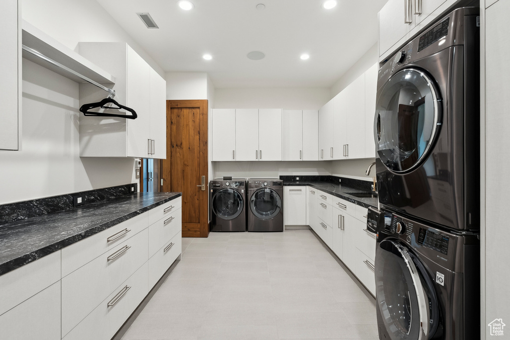 Laundry area featuring stacked washer and clothes dryer, a sink, recessed lighting, and light flooring