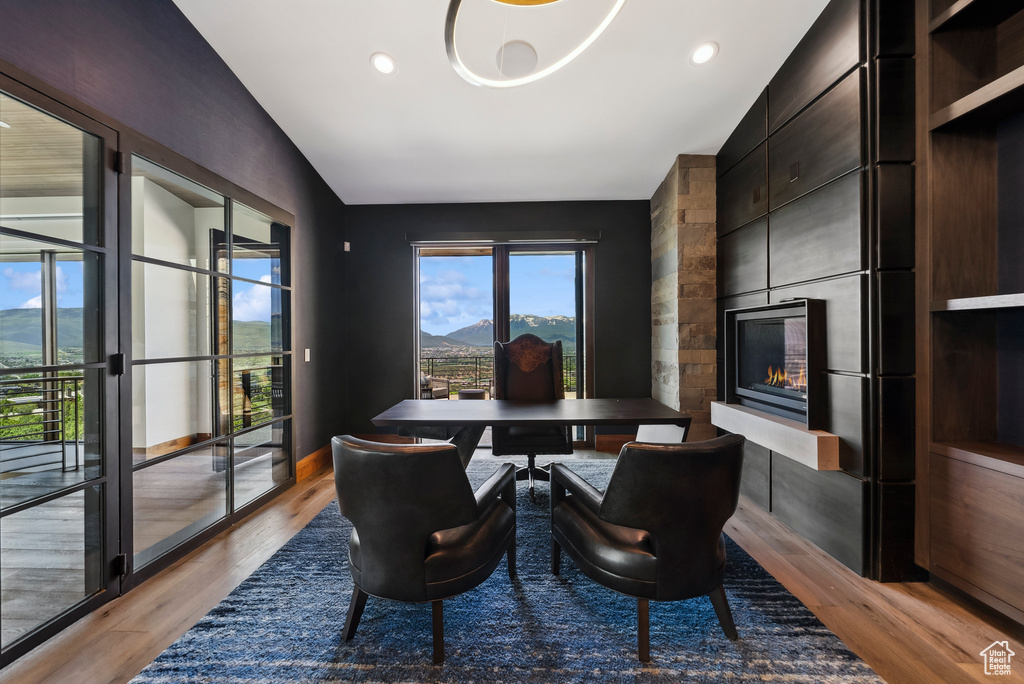 Dining area featuring light wood finished floors, a large fireplace, lofted ceiling, a mountain view, and recessed lighting