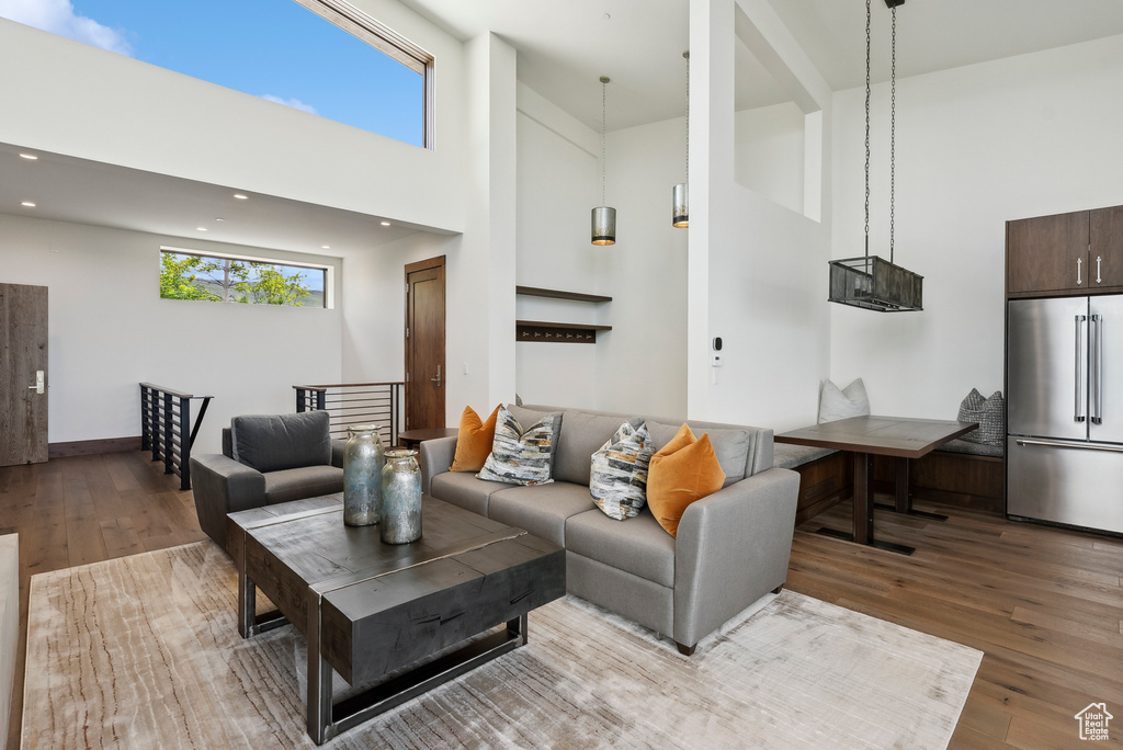 Living area with a high ceiling, wood finished floors, and recessed lighting