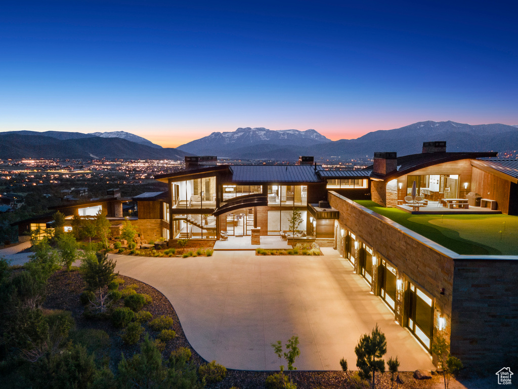 View of front of property featuring a mountain view, curved driveway, a standing seam roof, and a chimney