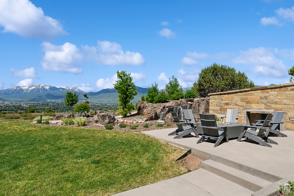 View of grassy yard featuring a mountain view and a patio area