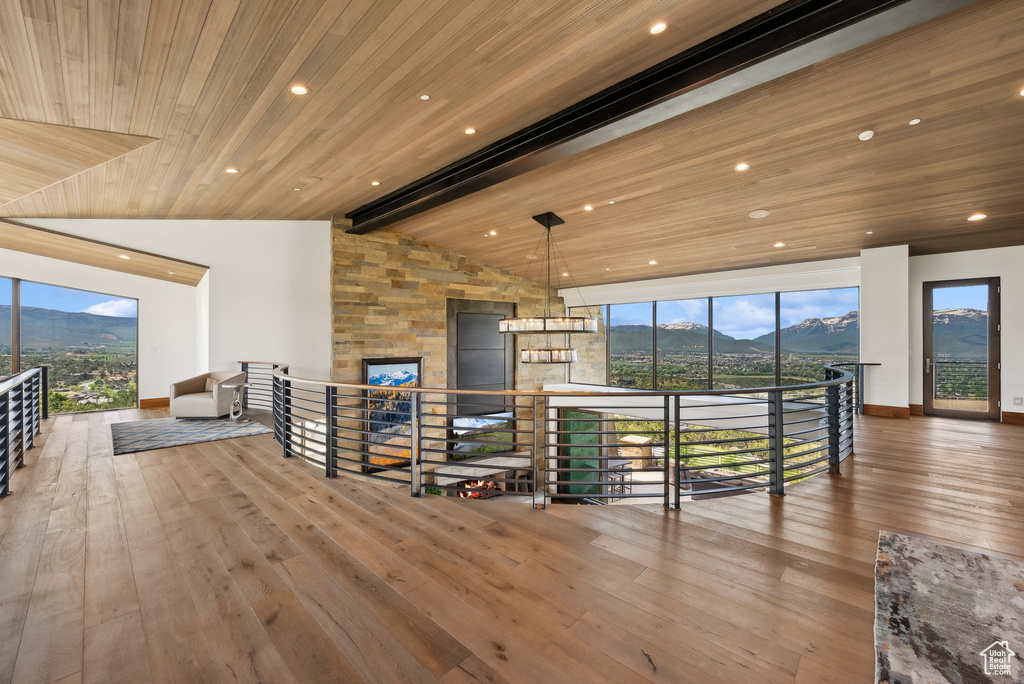 Living area with wood ceiling, a mountain view, wood-type flooring, plenty of natural light, and recessed lighting