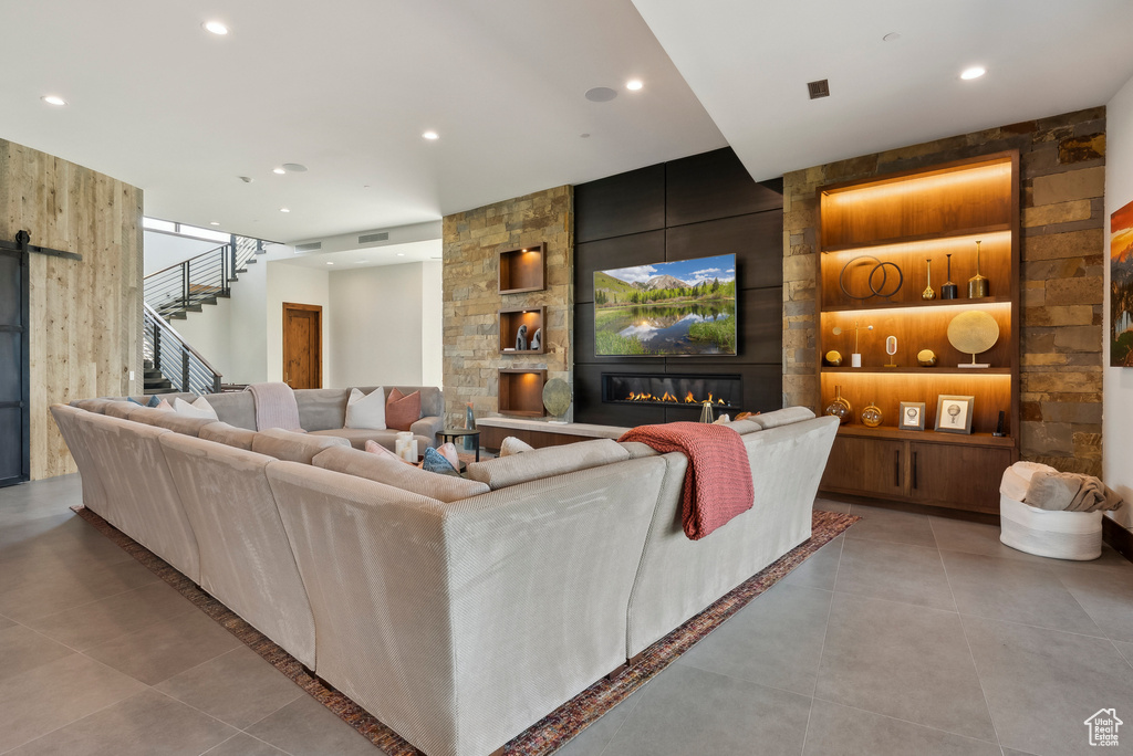 Living room with stairway, built in features, recessed lighting, a large fireplace, and tile patterned floors