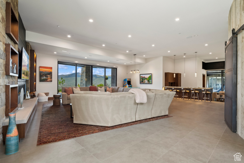 Living area featuring a barn door, recessed lighting, a large fireplace, and light tile patterned floors