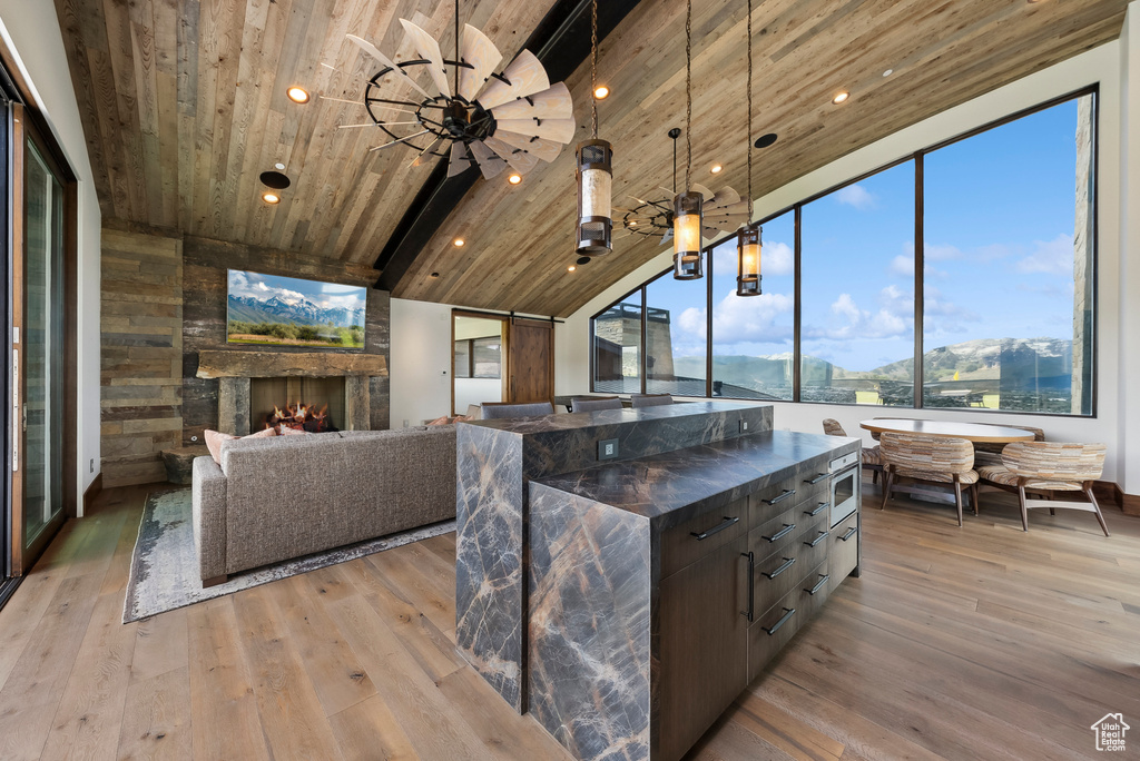 Kitchen featuring wood ceiling, light wood-style floors, lofted ceiling, a center island, and decorative light fixtures