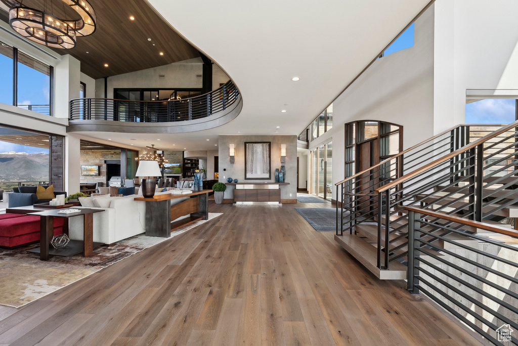 Foyer entrance featuring a high ceiling, wood-type flooring, stairway, a chandelier, and recessed lighting