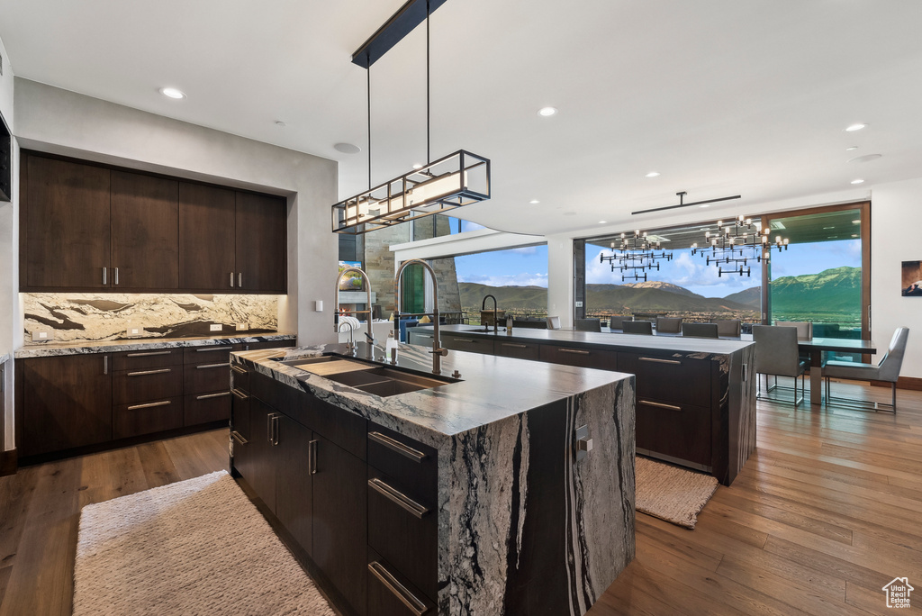 Kitchen featuring a kitchen island with sink, a chandelier, a sink, tasteful backsplash, and recessed lighting