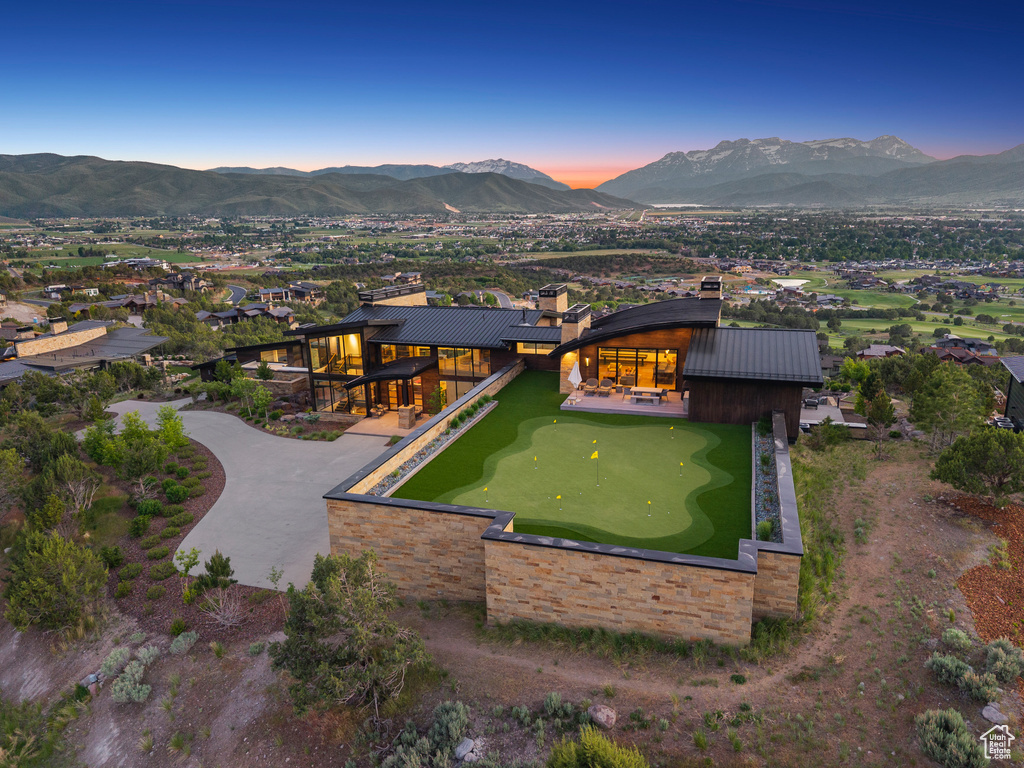 Back of house at dusk featuring a mountain view and a putting green