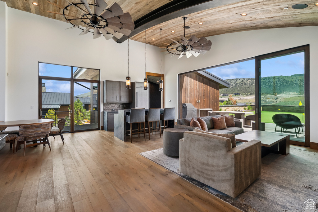 Living area featuring high vaulted ceiling, wood-type flooring, beamed ceiling, and ceiling fan